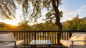 Eine Terrasse mit Tisch und zwei Stühlen mit Blick auf eine natürliche Landschaft aus Bäumen und Hügeln.