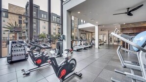 Ein Fitnessstudio mit verschiedenen Trainingsgeräten, großen Fenstern und modernem Interieur.