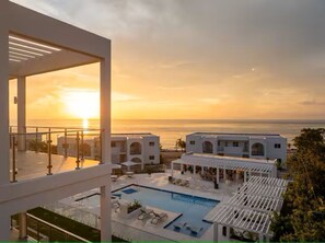 Ein Resort mit Pool, Außenbereich und Blick auf das Meer bei Sonnenuntergang.