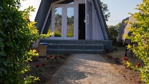 A modern, triangular-shaped building with a paved pathway leading to a door. - Dhauladhar View Village Resort (Dharamshala)