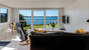 Ein modernes Wohnzimmer mit einem schwarzen Ledersofa, einem kleinen runden Tisch und einem an der Wand befestigten Fernseher.