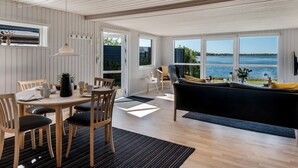 Ein modernes Interieur mit Essbereich, einer Couch und großen Fenstern mit Blick auf das Meer.