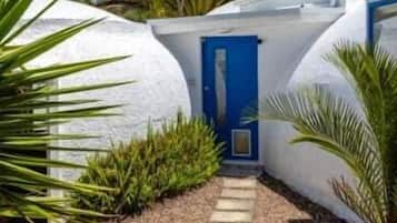 A modern building with a white exterior, a blue door, and a stone pathway leading to the entrance.