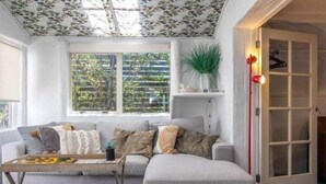Un salon avec un canapé, une table basse, une plante et une porte dotée d’un luminaire.