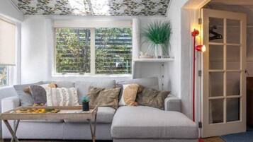 A living room with a sofa, a coffee table, a plant, and a door with a light fixture.