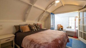 A bedroom with a bed, nightstand, and a chair. - Santorini on Sea View by Waiheke Pure - Close to beach, dome house, spacious and stylish (Waiheke Island)