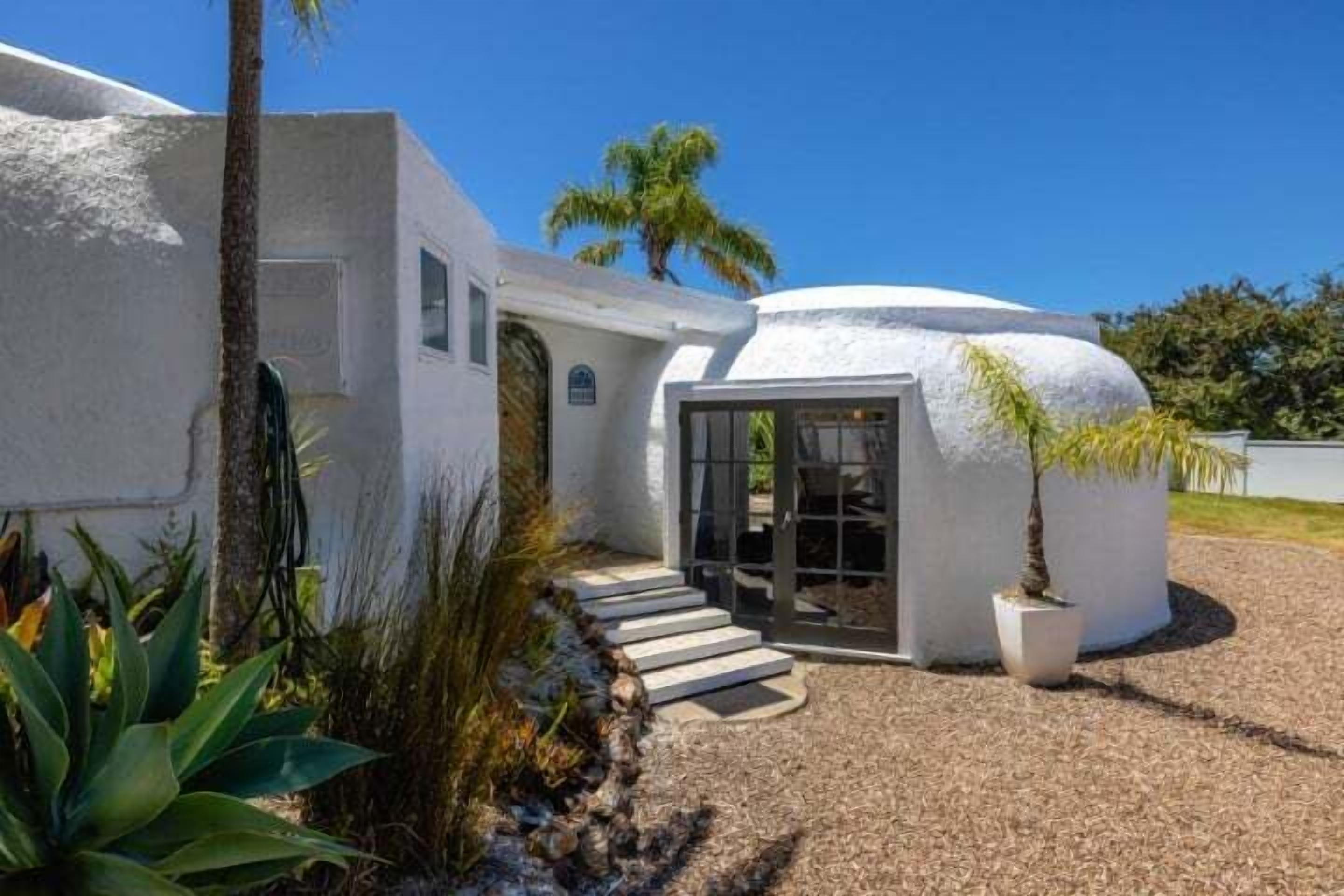 A modern house with a unique spherical structure, a stone staircase, and a potted plant.