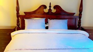 Ein Himmelbett mit Holz Kopfteil und weißer Bettwäsche.