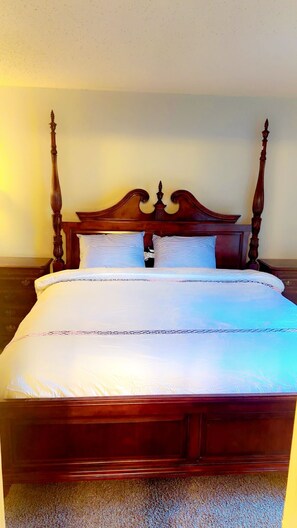 Ein Himmelbett mit Holz Kopfteil und weißer Bettwäsche.