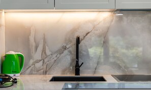 A kitchen with a marble backsplash, a green electric kettle, and a black faucet. - White Escape 3BR Luxury Lalzi Beach Villa (Ishëm)