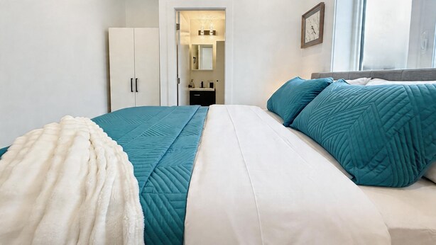 A bedroom with a bed, a wardrobe, a mirror, and a window. - Vancouver Katherine 2BD 2BA Laneway Home (Vancouver)