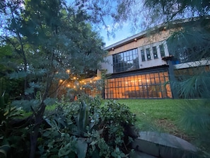 A modern building with large windows and a well-maintained garden.