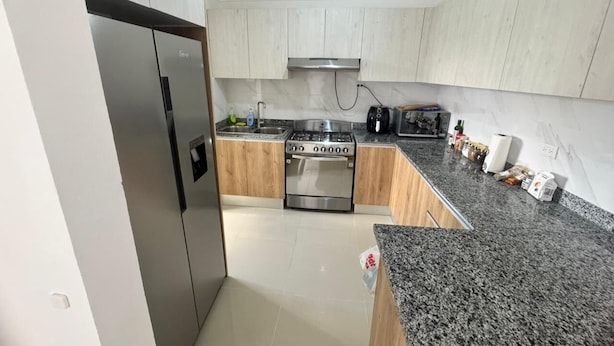 Eine moderne Küche mit Edelstahlherd, Backofen und Spüle, Holzschränken und Granit Arbeitsplatten.