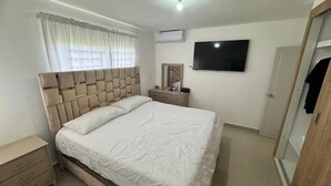 Ein Schlafzimmer mit Bett, Nachttisch, Kleiderschrank und Fernseher an der Wand.