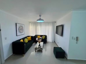 A modern living room with a sofa, a coffee table, and a television.