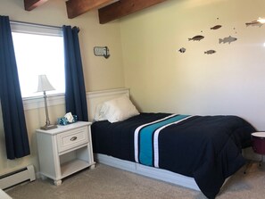 Una camera da letto con un letto, un comodino, una lampada e un decoro a parete raffigurante pesci.
