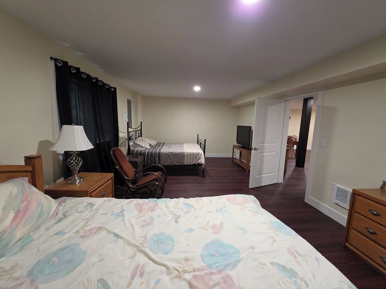 Une chambre à coucher avec un grand lit, une chaise, un bureau, une télévision et une armoire.