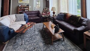 Ein geräumiges Wohnzimmer mit hohen Decken, großen Fenstern und einem gemütlichen Kamin.