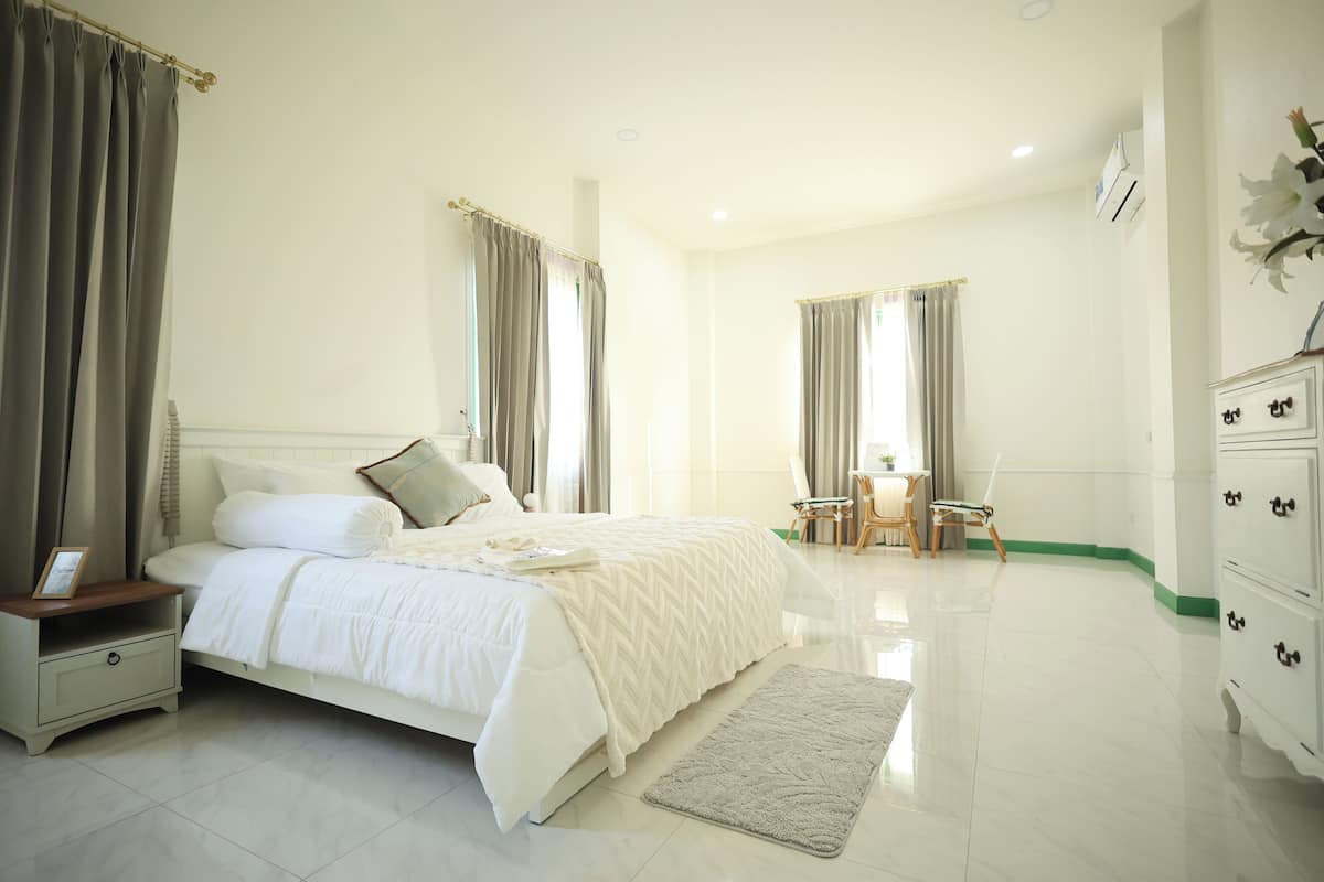 Une chambre à coucher comprenant un lit, une table de chevet, une commode et une petite table avec des chaises.