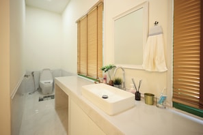 A bathroom with a sink, mirror, towel rack, toilet, and shower.