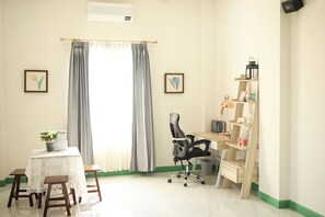 A room with a desk, chair, and a small table with a plant.