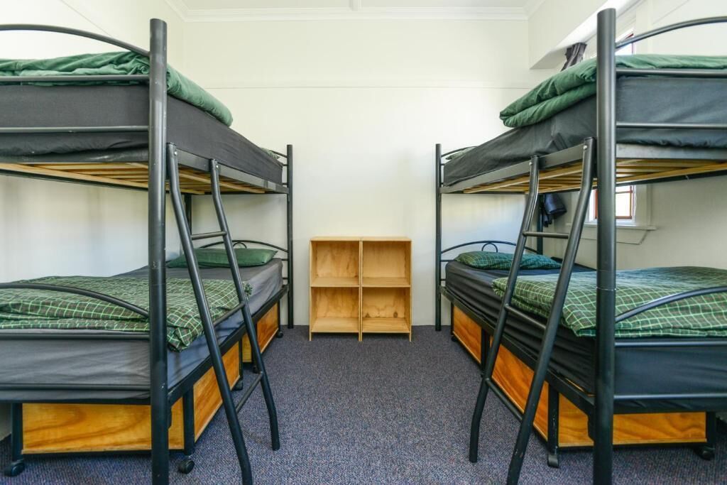 Een kamer met drie stapelbedden, een houten schapenkast en een vloerbedekking.