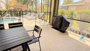 Un patio cubierto con piscina, sillas de descanso y una parrilla.