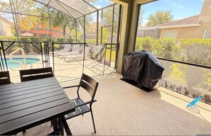 A covered patio with a pool, lounge chairs, and a barbecue grill. - Sunset Swims Disney Dreams-modern Family Oasis (Davenport)