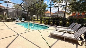 Una piscina al aire libre techada con sillas de descanso, una escalera de piscina y vistas a casas al fondo.