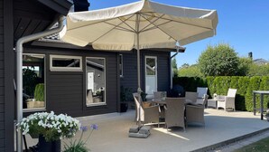 A patio with outdoor furniture, a large umbrella, and potted plants. - 4 Star Holiday Home in Solvesborg (Sölvesborg)