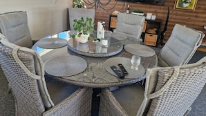 A round glass table with wicker chairs, a potted plant, candles, and a remote control. - 4 Star Holiday Home in Solvesborg (Sölvesborg)