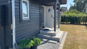 A house with a grey exterior, a visible number '5254', a front door, a small porch, and a gravel driveway. - 4 Star Holiday Home in Solvesborg (Sölvesborg)
