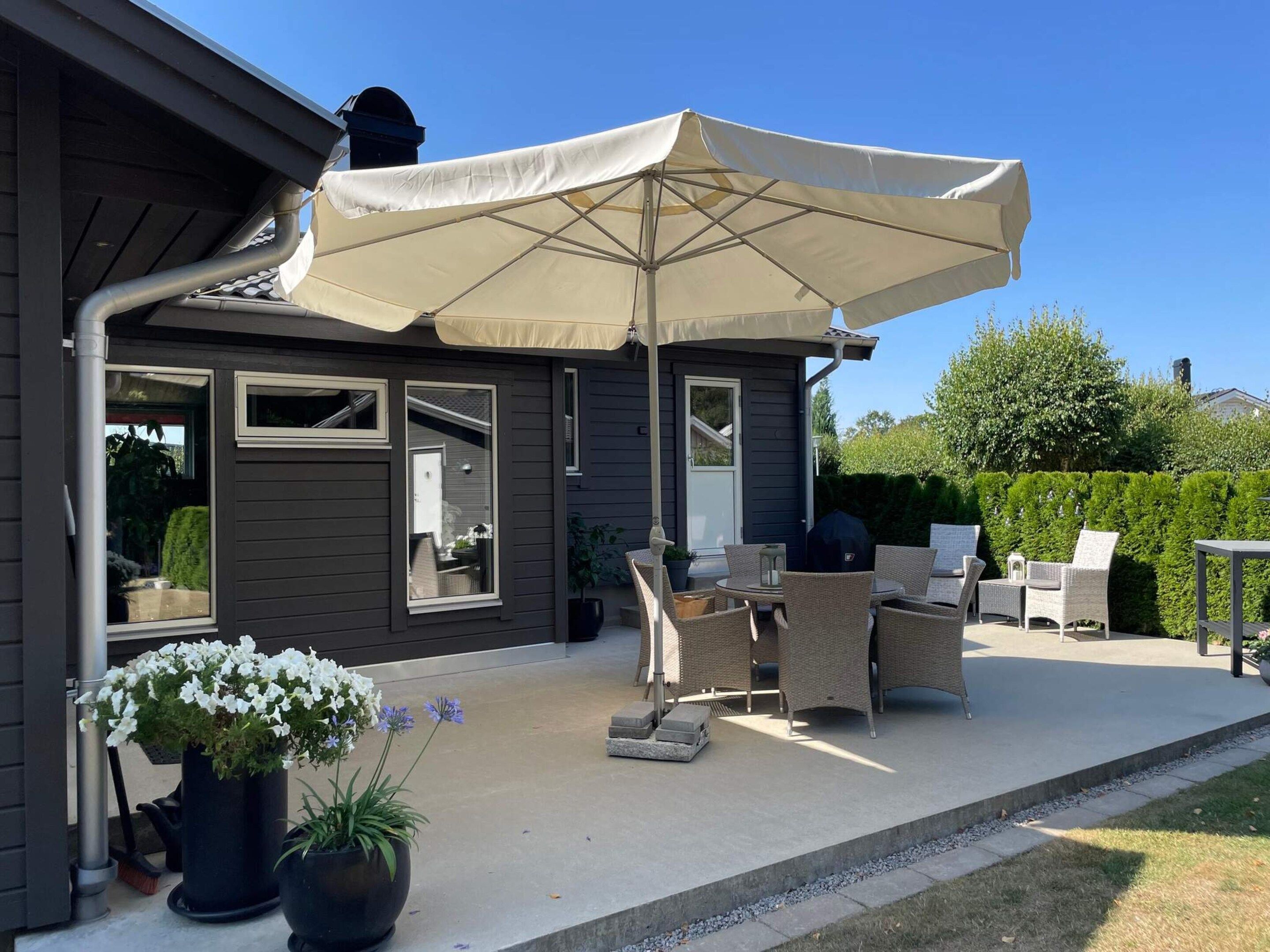 A patio area with outdoor furniture, a large umbrella, and potted plants.