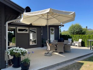 A patio area with outdoor furniture, a large umbrella, and potted plants. - 4 Star Holiday Home in Solvesborg (Sölvesborg)