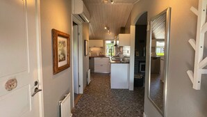 A hallway leading to a kitchen with white cabinets, a radiator, and a framed picture on the wall. - 4 Star Holiday Home in Solvesborg (Sölvesborg)