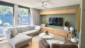 Een moderne woonkamer met een bank, fauteuils, een salontafel en een televisie.