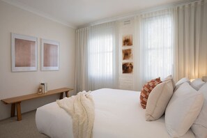 Un dormitorio con una cama grande, una mesita de noche y un banco.