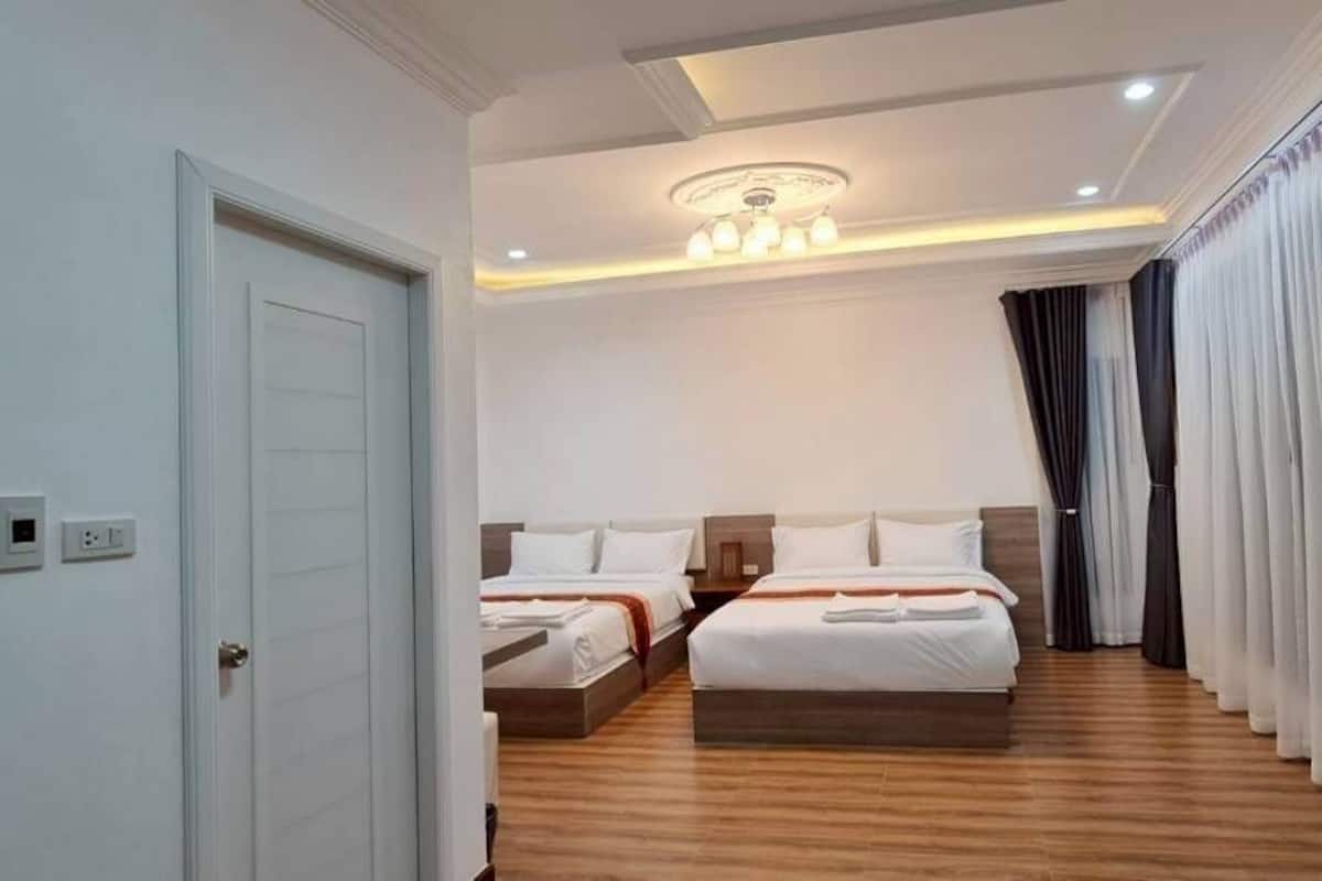 Una habitación de hotel con dos camas, una araña y un ventanal con cortinas.
