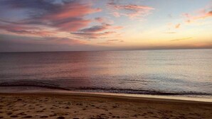 Una playa con un mar tranquilo y un cielo al atardecer.