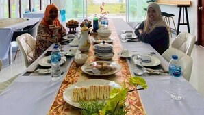 Un salón de conferencias con una larga mesa dispuesta para una reunión, sillas y una planta en maceta.