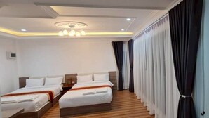 Habitación de hotel con dos camas, suelo de madera, lámpara en el techo y cortinas.