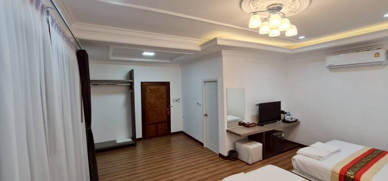 A hotel room with a bed, a desk with a computer, a television, and a wardrobe.
