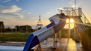 Un parque infantil con un tobogán y una estructura que muestra el letrero 'NARA PARADISE' al fondo.