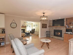 A living room with a fireplace, a chandelier, and a television.