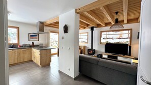 Eine moderne Küche mit Holzschränken, einem eingebauten Herd und einem Essbereich mit Tisch und Stühlen.
