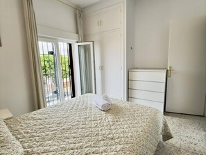 A hotel room with a bed, a wardrobe, and a door leading to a balcony.