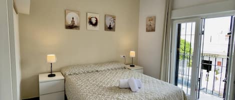 A hotel room with a bed, two bedside tables, a window, and wall art.