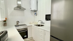 Una cocina moderna con lavavajillas integrado, refrigerador de acero inoxidable y microondas.