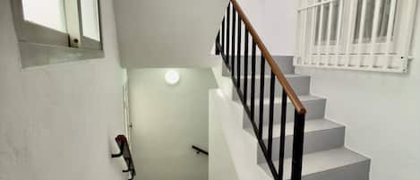 A staircase with white steps and black railings, leading to a landing with a door and a window.