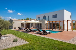 A modern house with a swimming pool, outdoor seating, and a well-maintained lawn. - Villa Royal Green (Rasa)